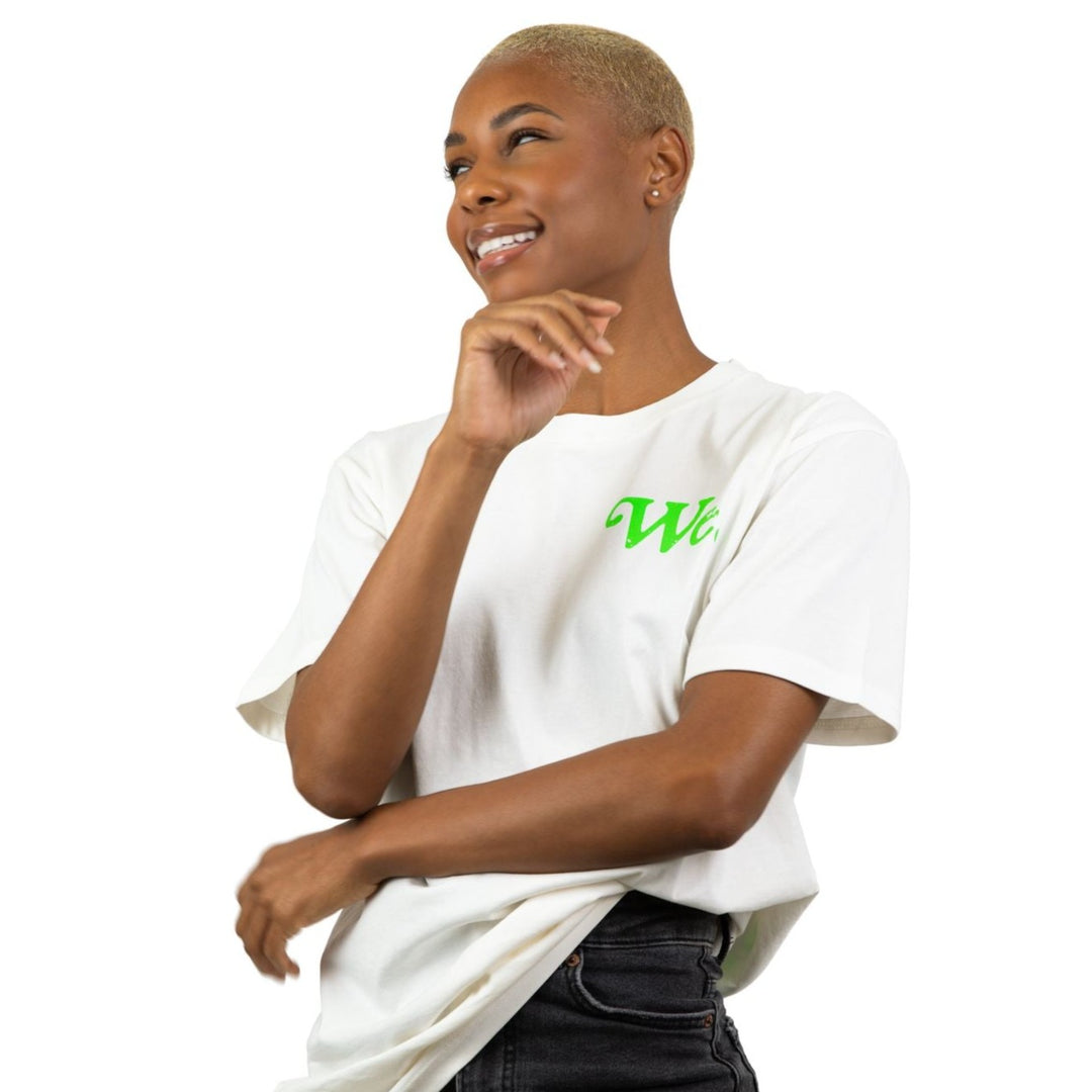**AltImage: We. Are The Ones Sand color tee with  green printing.  The shirt features the word "We." displayed in a minimalist fashion on the front in a gorgeous lime green. A young black young woman who is smiling and looking off to the side.  Her pose exudes self-assurance.  This image captures the essence of empowerment and promotes the message of being united.